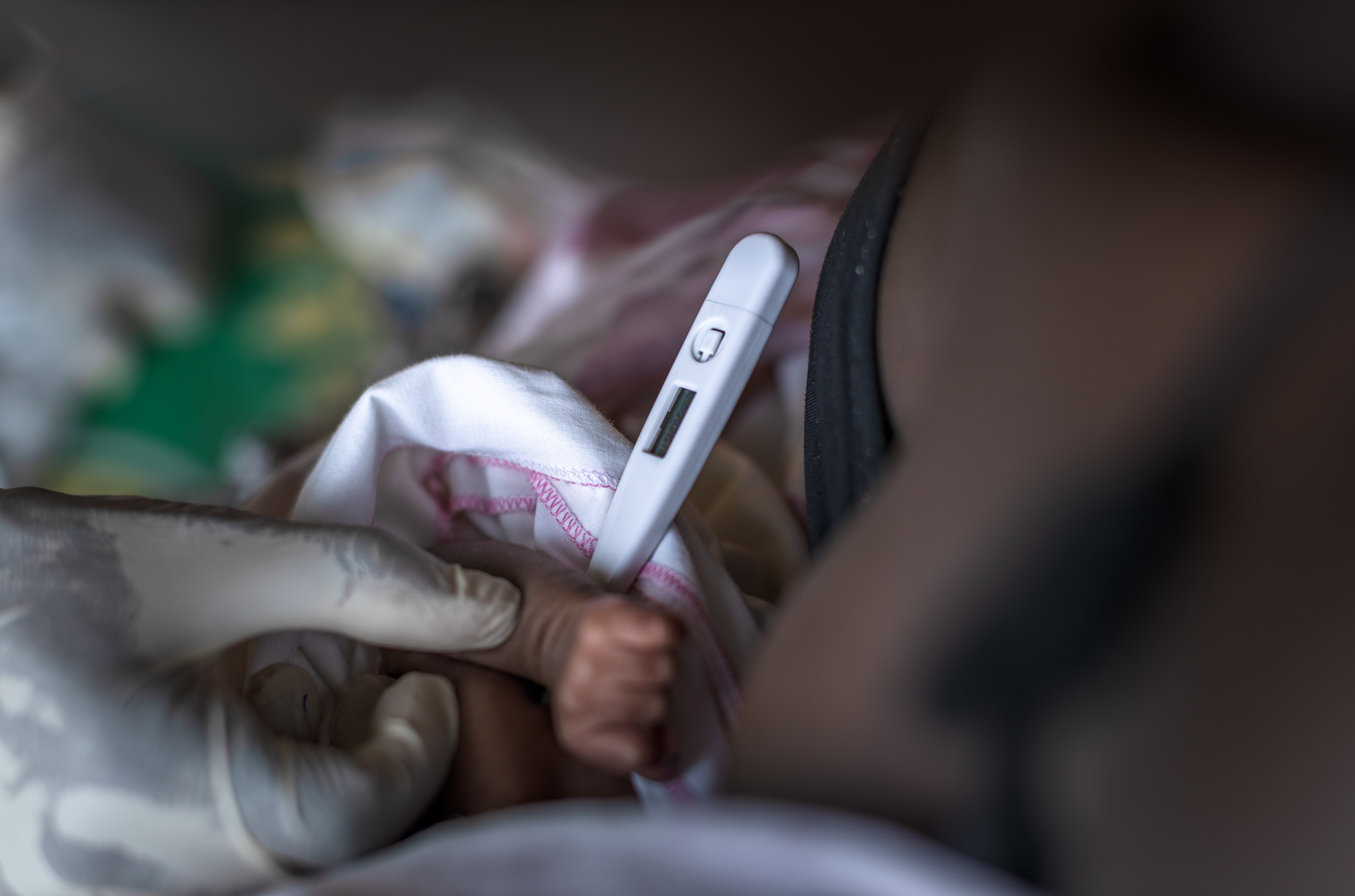 Frontline worker measures a baby’s temperature using a thermometer