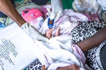 Frontline worker checking a newborn’s oxygen level with a pulse oximeter